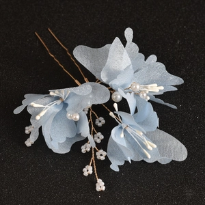 Close-up of blue tulle flower hair pins with white pearls and gold metal branches