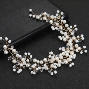 Detail of handmade bridal hair vine with pearls, crystals and gold wire on black background