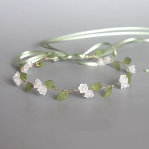 Close-up of handmade lily of the valley hairband with white flowers and green leaves