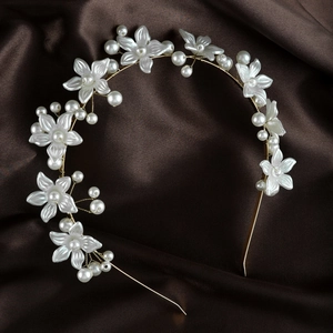 Detail of floral headband featuring pearl accents and gold frame on satin background