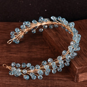 Detailed shot of sky blue crystal beads on gold wire bridal headband over wood