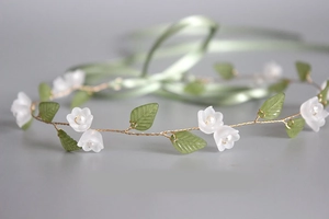 Detailed macro view of handmade lily of the valley headband with white resin flowers and pearls