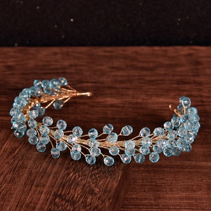 Macro shot of gold vine bridal headband with blue faceted crystal beads on wood