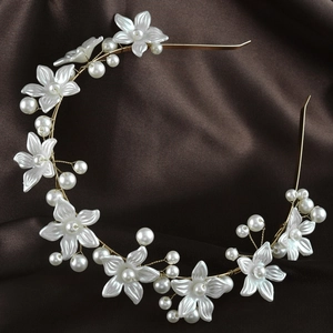 Elegant gold headband with white silk flowers and pearls on a silk background
