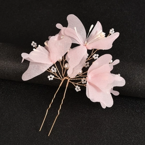 Macro detail of bridal hair pin with pink chiffon flowers and pearl accents on gold prongs
