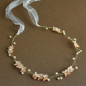 Close-up of handmade bridal headband with gold wire, pearls, and resin flower petals