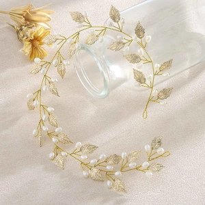 Detail shot of golden leaf hair vine with white pearls on a textured fabric background