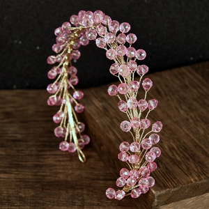 Detailed view of pink crystal beads and gold wire vine on a bridal hair headband