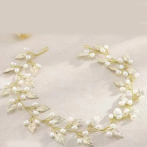 Detail of bridal hair vine with golden metal leaves and white faux pearls on soft wire