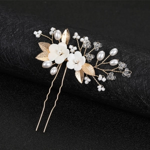 Handmade bridal hair pin with white ceramic flowers and golden leaves on black pedestal
