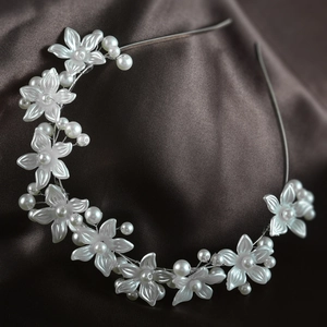 Close-up of elegant white floral resin flowers and faux pearl headband on silk