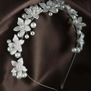 Close-up of elegant floral bridal headband with white petals and pearls on satin