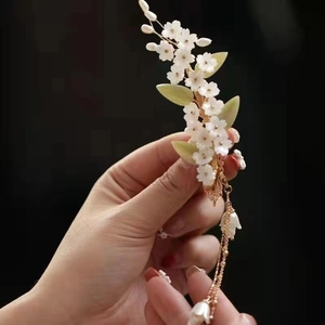 Pince à cheveux chinoise élégante avec fleurs blanches, feuilles vertes et longs pompons