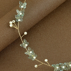 Detail of bridal headband with blue butterfly charms, pearls, and gold wire mesh craft