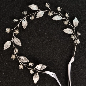 Makroaufnahme von Braut-Haarschmuck mit Silberblättern und Perlen auf schwarzem Grund