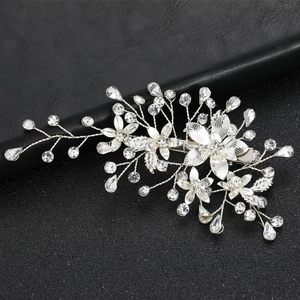 Silver bridal hair clip with metallic leaves and sparkling rhinestones on black background