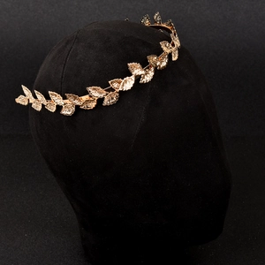 Detailaufnahme eines goldenen Haarreifs mit Blattdesign auf einem schwarzen Modellkopf