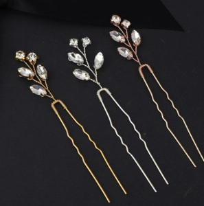 Detail of three U-shaped bridal hair pins in gold silver and rose gold with rhinestones