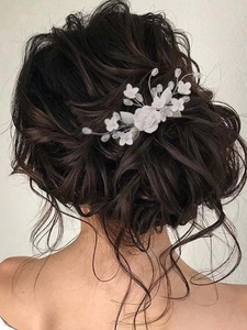 Romantic bridal hair comb featuring white ceramic flowers and silver leaves on a model