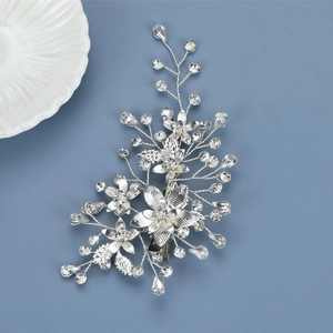 Silver bridal hair clip with intricate leaves and crystals on a blue background