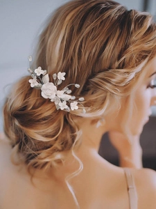 Elegant bridal hair comb with white matte clay flowers, crystals, and pearls on model