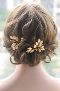 Elegant gold leaf hair pins set for weddings shown on a braided hairstyle for women