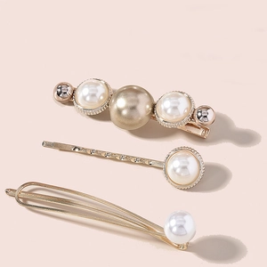 Three-piece gold metal hair clips set with elegant pearls on a soft pink background
