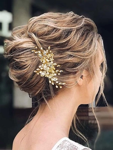 Vue détaillée d'un peigne de mariée avec perles et strass dans un chignon élégant à l'arrière