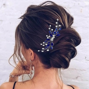 Detailed back view of a bride's updo styled with a blue gemstone and pearl hair comb