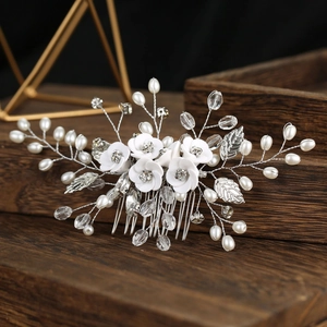 Détails d'un peigne à cheveux de mariée avec fleurs en céramique blanche et perles