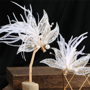 Détail de barrettes à plumes blanches avec dentelle, perles et fils dorés élégants