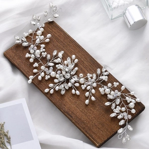 Handmade bridal hair vine with white pearls and crystals on a rustic wood background