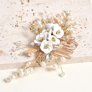 Détails de fleurs en céramique blanche et perles sur un peigne à cheveux de mariée