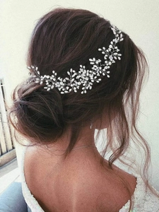 Detail view of a bridal hair vine with pearls and rhinestones on a low bun hairstyle
