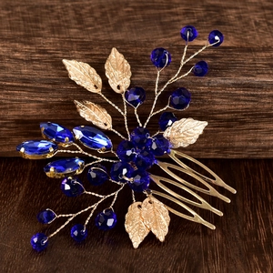 Close-up of golden leaf bridal hair comb with deep blue crystals on a rustic wood background