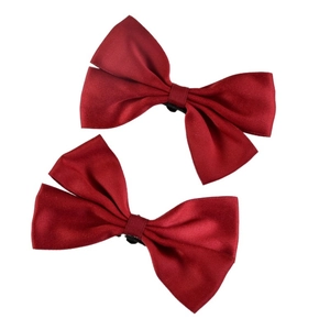 Detail view of two deep red satin bow shoe clips with a silky smooth finish for bridal decor