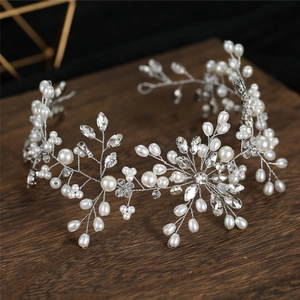 Elegant bridal pearl and crystal wedding hairpiece with silver vine leaf design on wood