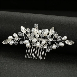 Détail d'un peigne à cheveux de mariée argenté avec perles à la main et cristaux