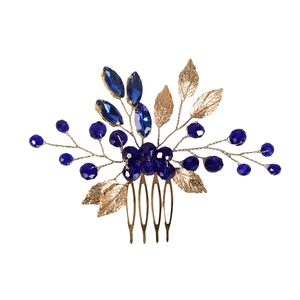 Detailed close-up of golden leaf hair comb with emerald green crystal accents for brides