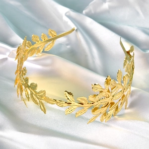 Elegant golden laurel leaf bridal headband with metallic texture on blue silk background