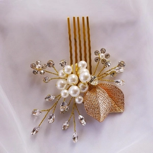 Détail d'un peigne de mariée avec feuilles dorées, perles et strass étincelants