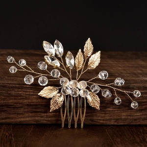 Detail of golden bridal hair comb with emerald green crystal beads and textured metal leaves