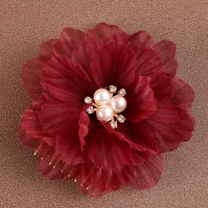 Détail d'un peigne à fleurs en tissu rouge foncé avec des perles et des strass brillants