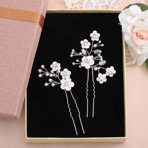Détail d'épingles à cheveux de mariée avec fleurs blanches, perles et cristaux fins