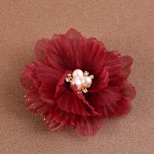 Détail d'un peigne à fleurs en mousseline bordeaux avec perles crème et dents dorées