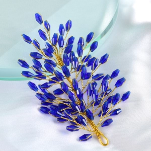 Detail of blue crystal leaf hair accessory with golden wire wrapping on silk