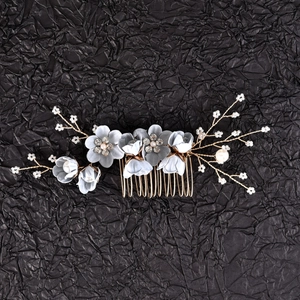 Detail of blue fabric flowers with pearls and gold wire branches on bridal hair comb