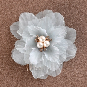 Détail d'un peigne à fleurs en tissu bleu clair avec perles et strass pour coiffure de mariée