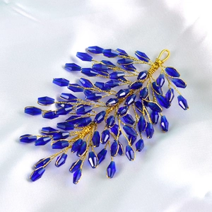 Detailed view of handcrafted dark blue crystal leaf hair accessory with golden wires