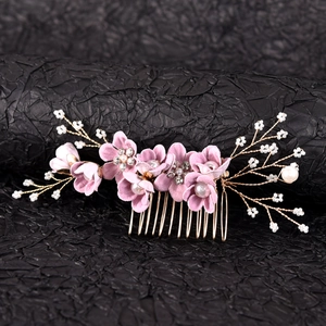 Detail of pink fabric flowers with crystal centers and white pearls on a gold bridal comb